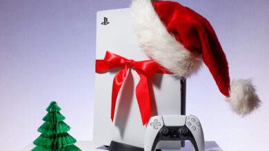 console de jeu Sony PlayStation 5 sur fond bleu blanc. Édition cadeau de Noël avec bonnet de Noel et ruban rouge