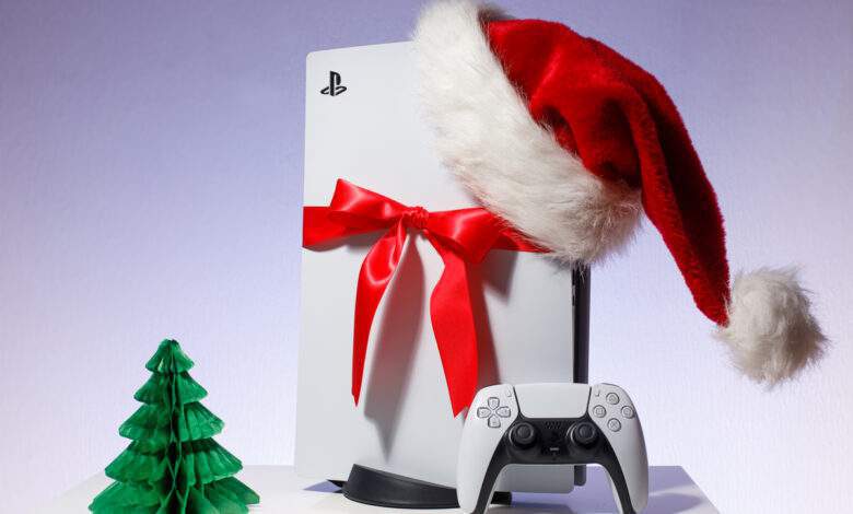 console de jeu Sony PlayStation 5 sur fond bleu blanc. Édition cadeau de Noël avec bonnet de Noel et ruban rouge