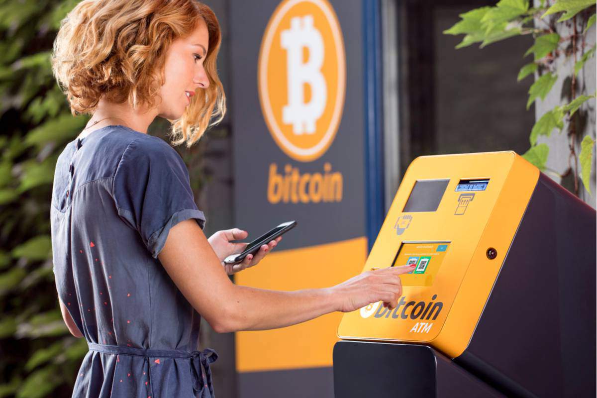Une femme devant un distributeur de Bitcoin