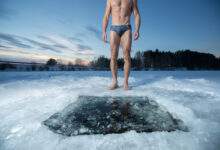Jeune homme debout près d'un trou de glace et prêt à nager dans l'eau d'hiver