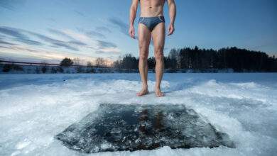 Jeune homme debout près d'un trou de glace et prêt à nager dans l'eau d'hiver