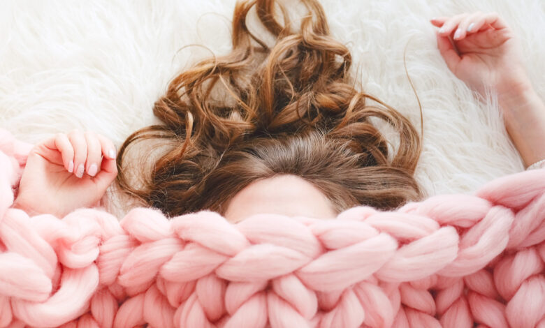 Une femme sous une couette rose lestée