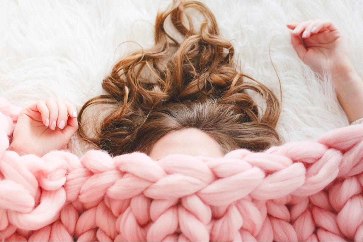 Une femme sous une couette rose lestée