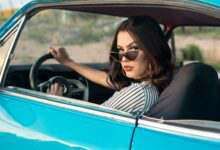 une femme avec des lunettes de soleil qui regarde par la fenêtre de sa voiture