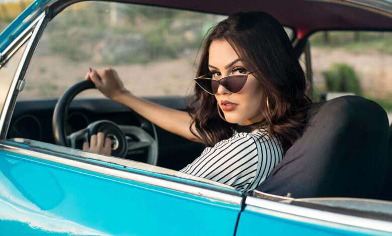 une femme avec des lunettes de soleil qui regarde par la fenêtre de sa voiture