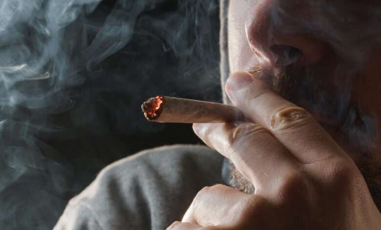 un homme qui fume un joint de cannabis