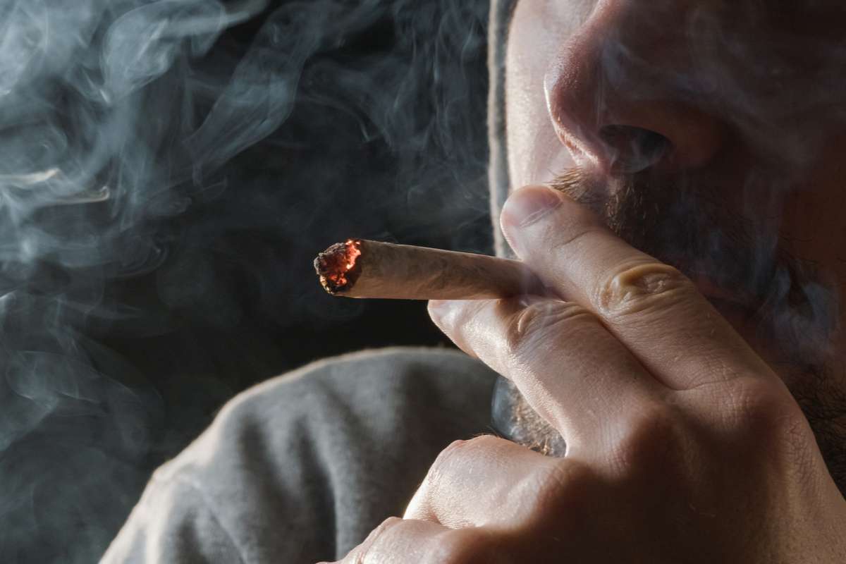 un homme qui fume un joint de cannabis