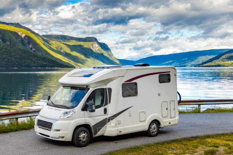 Un camping car sur la route devant un beau paysage avec un lac