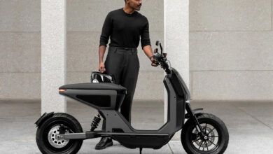 Un homme habillé en noir devant le scooter électrique Naon Zero-One