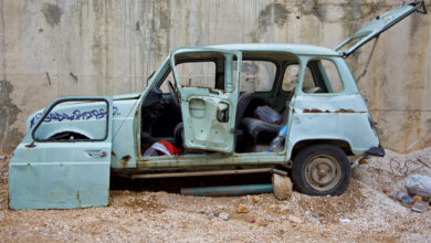 Une voiture 4L abandonnée avec des ordures.
