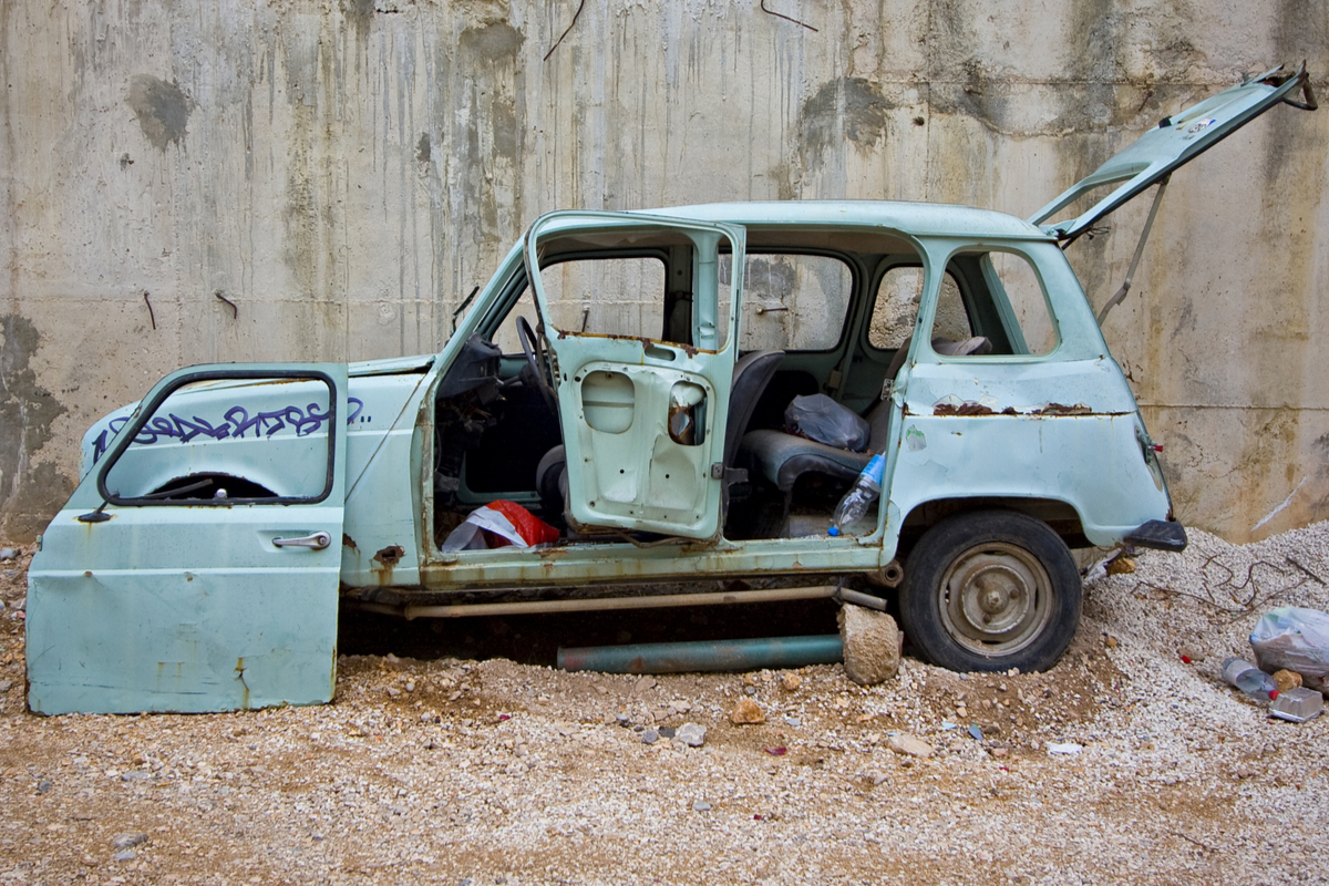 Une voiture 4L abandonnée avec des ordures.