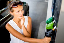 Une femme réfléchit devant une pompe de carburant