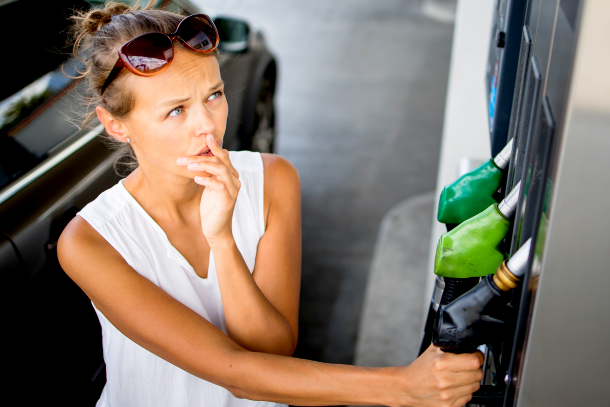 Une femme réfléchit devant une pompe de carburant