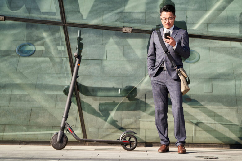 Un homme regarde son téléphone avec une trottinette électrique 