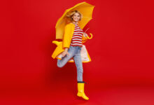 Une femme avec un parapluie jaune sur fond rouge