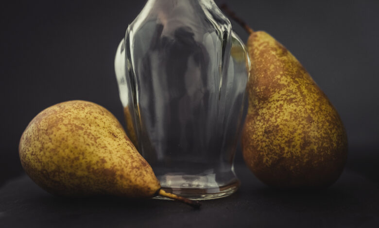 Une bouteille en verre et trois poires