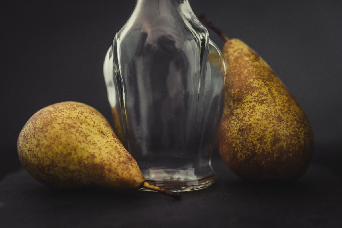 Une bouteille en verre et trois poires