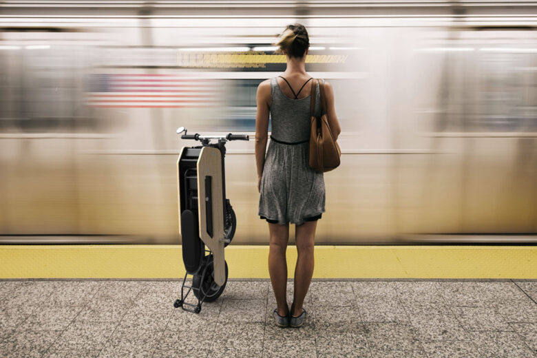 Une femme dans le métro avec un scooter électrique en bambou plié