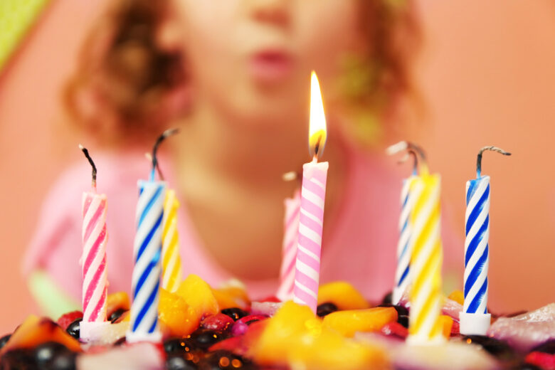 Un enfant souffle des bougie sur un gâteau 