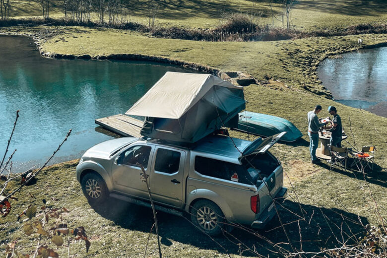 Une voiture sur le bord d'un lac avec une tente de toit