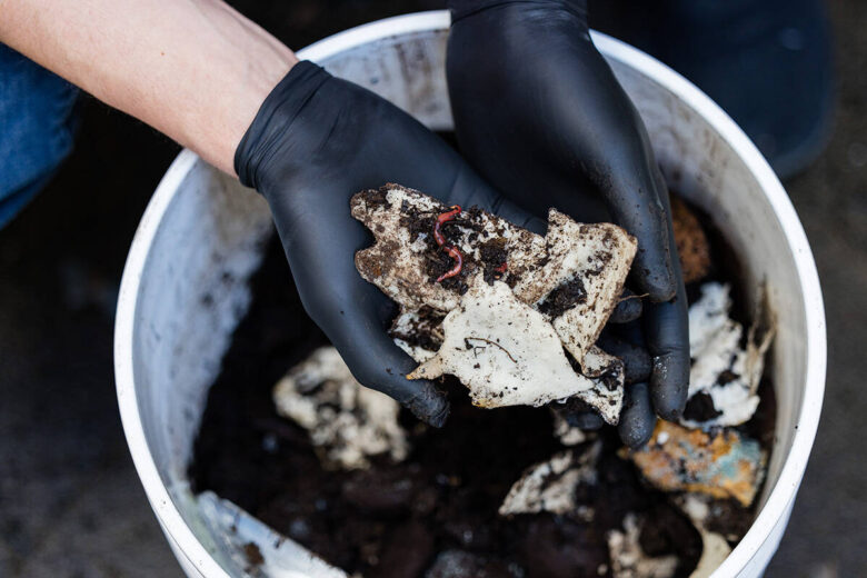 Un bac à compost montre des morceaux de contenants à emporter en morceaux fabriqués à partir du bioplastique de Bioform.