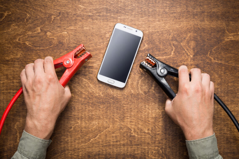 un homme essaye de recharger son téléphone avec des pinces de batterie