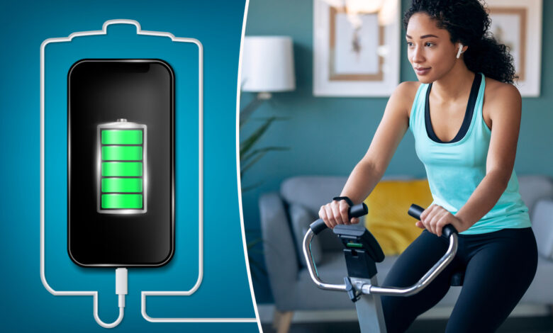 une femme pédale sur un vélo d'appartement pour recharger un téléphone