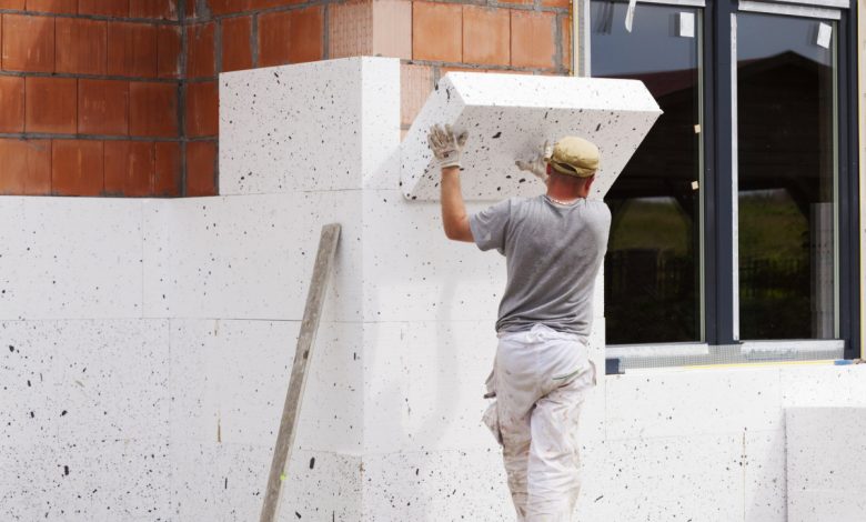 Un Homme Installe Une Couche D'isolation Thermique Sur Le Mur De L