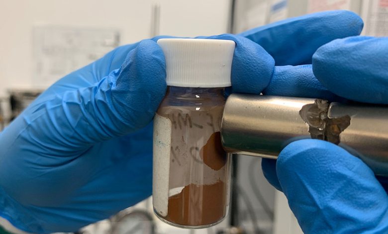 Un aimant attire le matériau que les scientifiques ont utilisé pour fabriquer des adsorbants qui éliminent les microplastiques et les polluants dissous de l'eau.