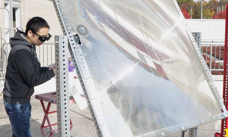 Peng Zhou utilise une grande lentille pour concentrer la lumière du soleil sur le catalyseur