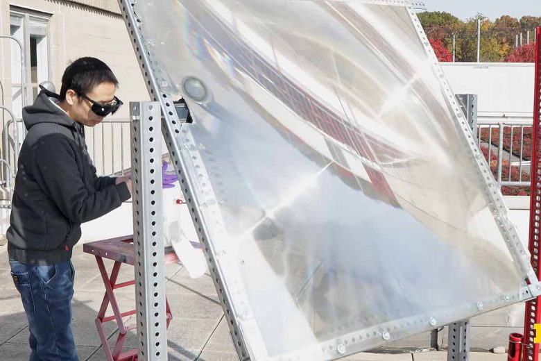 Peng Zhou utilise une grande lentille pour concentrer la lumière du soleil sur le catalyseur