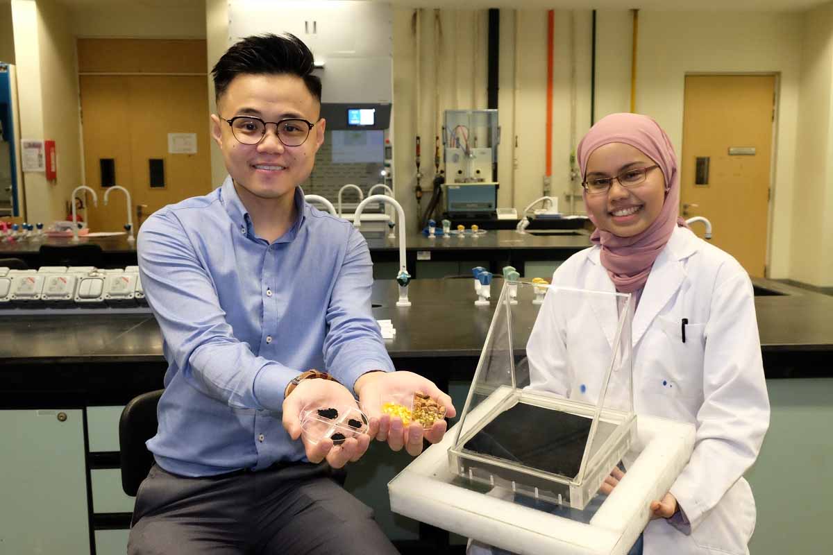 Le professeur Edison Ang (à gauche) avec des échantillons de déchets de fruits et de carbures de molybdène assisté d'une collègue qui tient un alambic solaire.