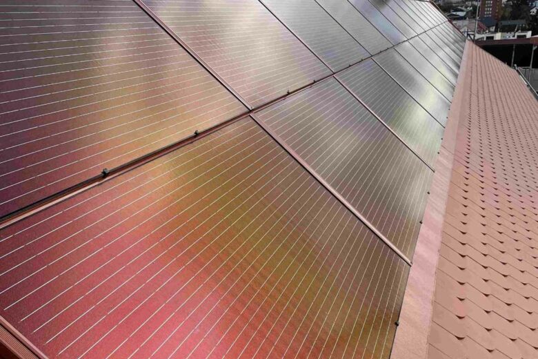 Gros plan sur l'intégration d'un panneau solaire rouge sur un toit.