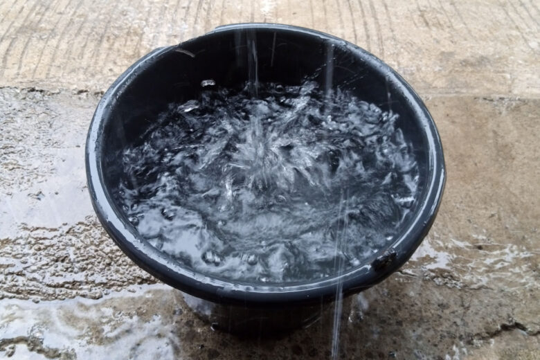 Des sceaux et des gouttières pour récupérer l'eau de pluie sur un balcon. 