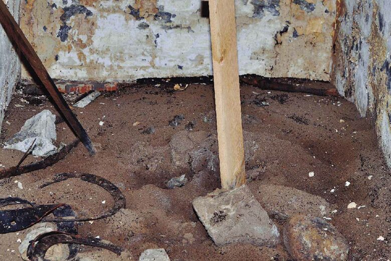 Le monticule de terre, presque déserté par les fourmis, au fond du bunker, quatre mois après la mise en place d'une passerelle en bois pour les libérer. Des « cimetières de fourmis » sont visibles autour du monticule et à côté des murs.