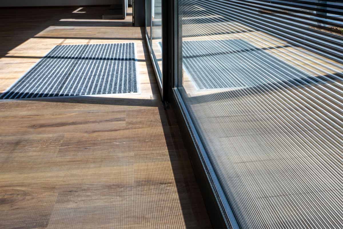 Des stries inclinées à l'aspect miroir argenté sont appliquées sur un vitrage feuilleté pour servir de protections solaires. Cette solution peut être utilisée dans des structures à double vitrage, offrant des performances supplémentaires en termes d'isolation acoustique ou de résistance aux intrusions.