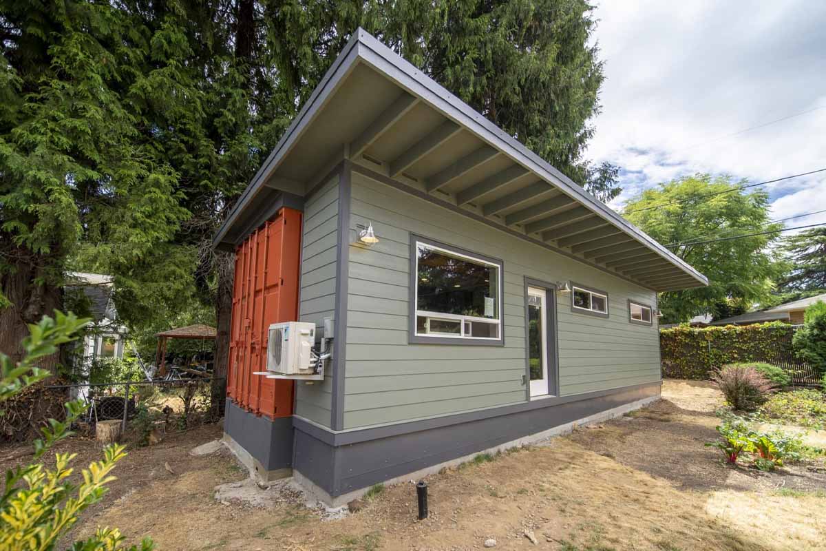 Une maison container hybride qui comprend un conteneur d'expédition à l'arrière et une partie à ossature de bois à l'avant.