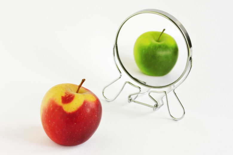 Pomme rouge regardant dans le miroir et se voyant comme une pomme verte - Concept de daltonisme.