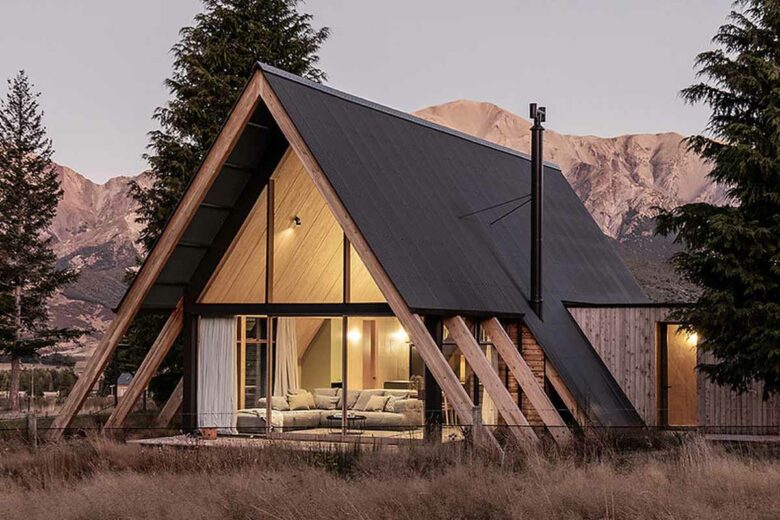 Une maison en A nichée entre deux arbres.