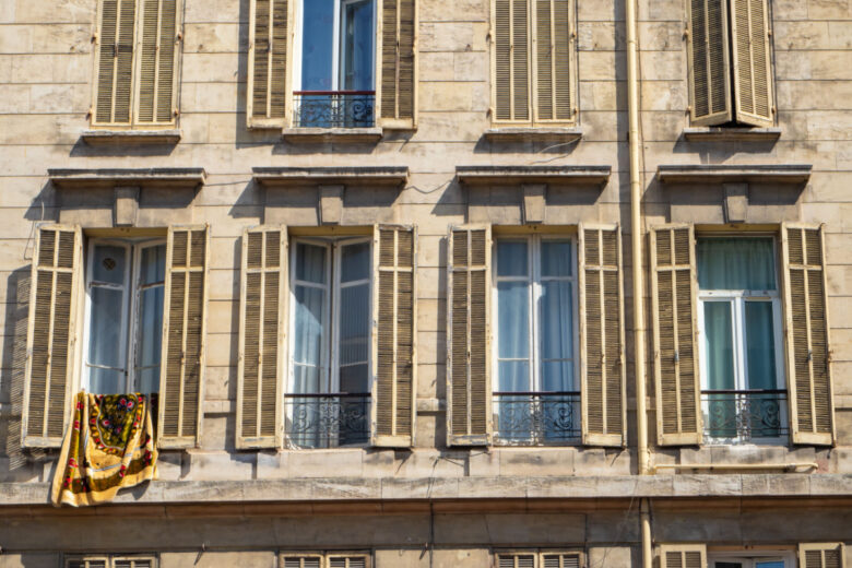 Vue d'ensemble d'une façade historique d'un immeuble d'habitation et ses volets anciens à Marseille.