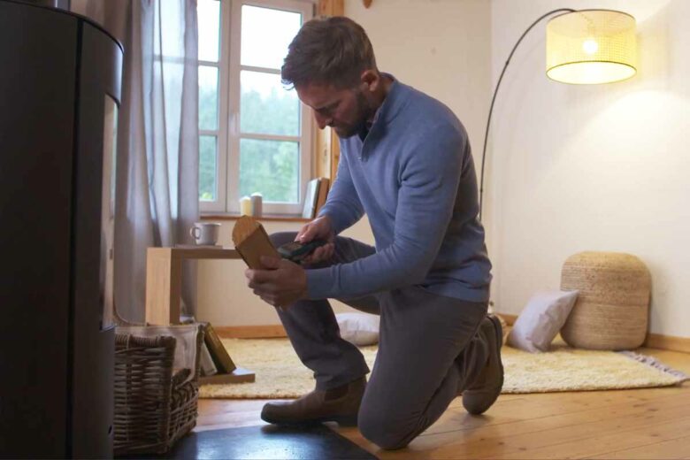 Un homme qui contrôle le taux d'humidité de son bois de chauffage.