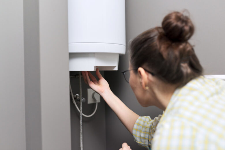 Une femme qui règle le thermostat de son chauffe-eau.