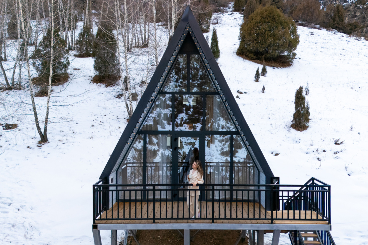 Une maison en A dans une vallée enneigée.