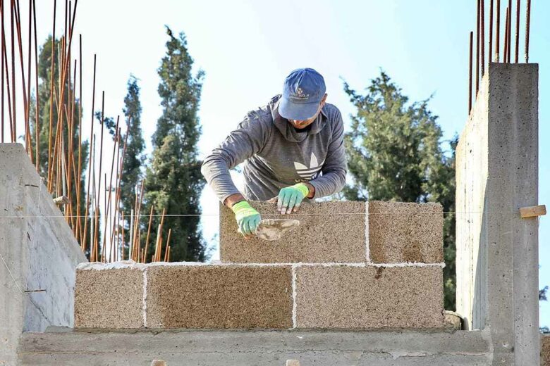 Un ouvrier du bâtiment réalisant un mur en bloc de béton chanvre.