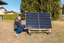 Un homme qui installe un panneau solaire sur un support à roulettes fait maison.