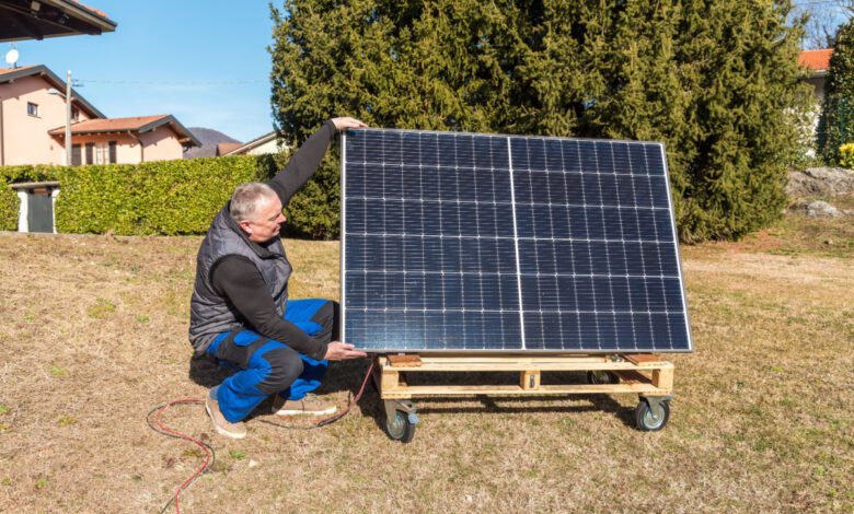 Un homme qui installe un panneau solaire sur un support à roulettes fait maison.