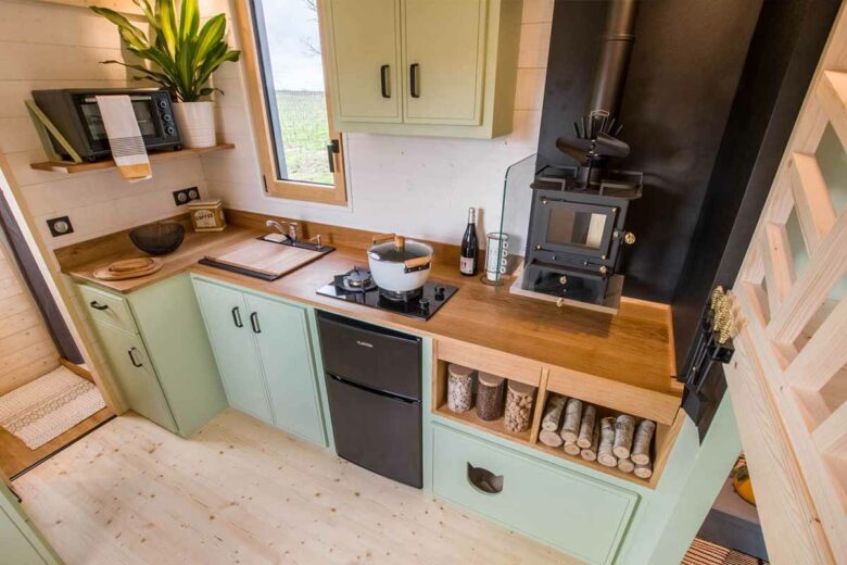 Une cuisine équipée, avec un poêle à bois et un tiroir escamotable pour les chats.