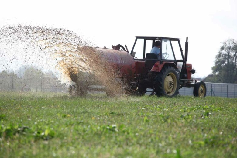 Un fermier qui fertilise ses champs avec de la bouse de vache.