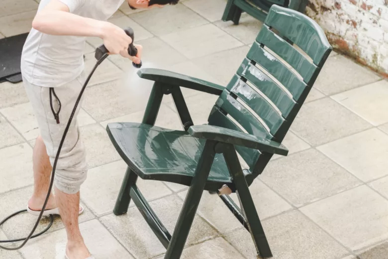 Un homme qui nettoie ses éléments de salon de jardin.