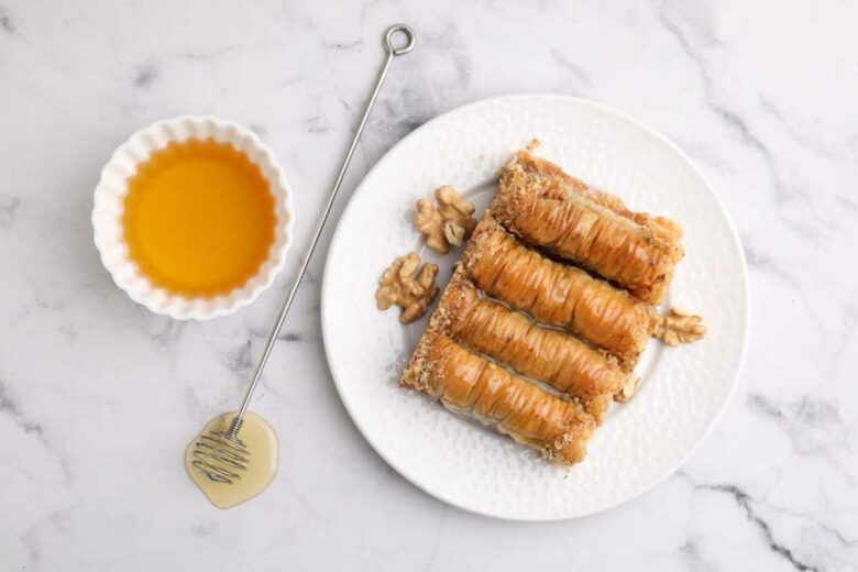 Une cuillère à miel en acier inoxydable pour servir le délicieux nectar sur une pâtisserie orientale.